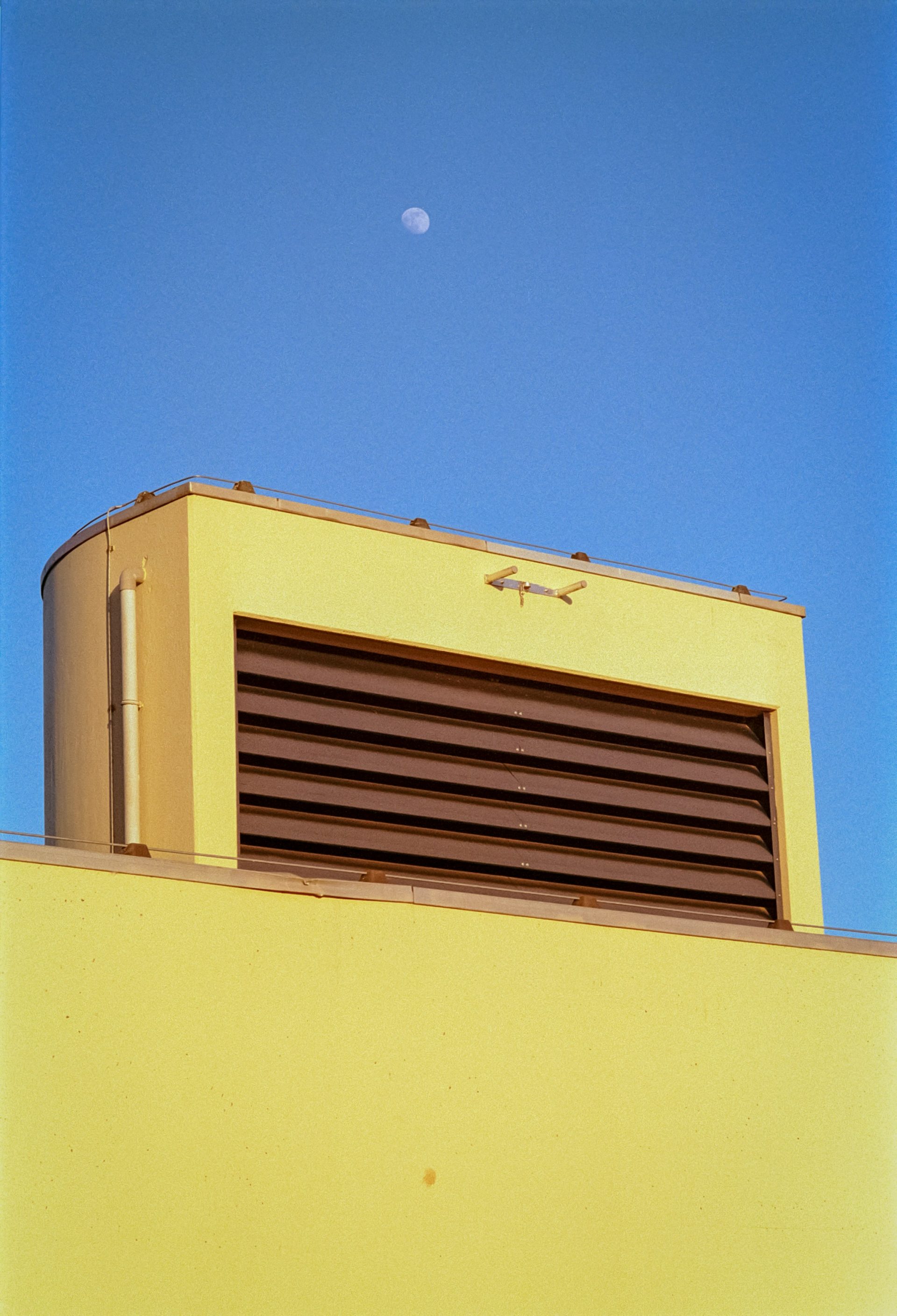 a yellow building with a half moon in the sky